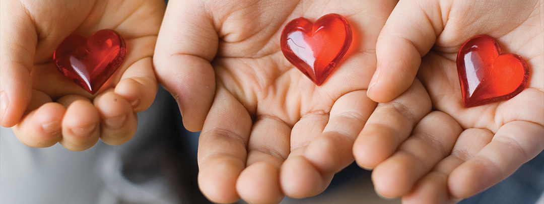 3 child's hands holding glass hearts