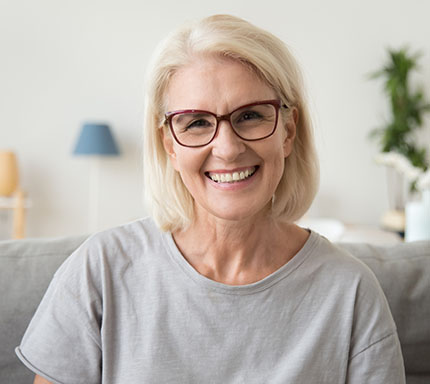 Middle aged woman with light coloured hair and glasses smiling