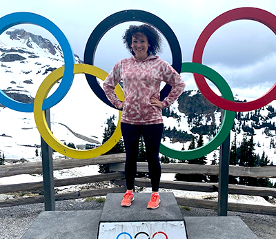 Karley standing on a podium with the Olympic rings behind her.