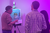Two guests watching an artist at an Art Battle