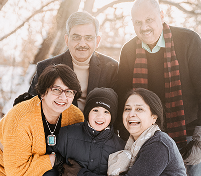 Shivika's family, lovingly embracing in a wintery landscape with warm clothing on.