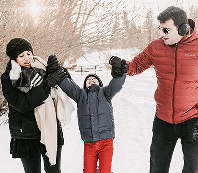 Shivika and her partner walking with their son down a snow-covered path.